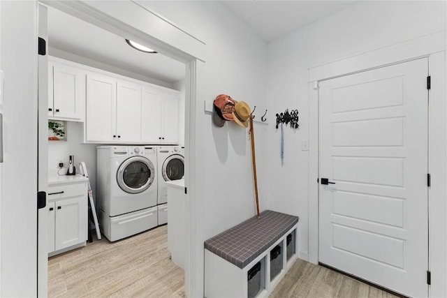 laundry area with washer and dryer, cabinet space, and light wood-type flooring