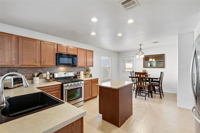6801 Campina Xing, Del Valle, TX 78617 - kitchen with black microwave, stainless steel gas range, backsplash, light countertops, and brown cabinets