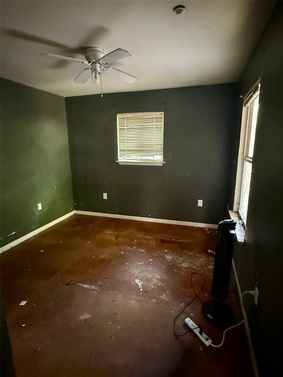 empty room with unfinished concrete flooring, baseboards, and a ceiling fan