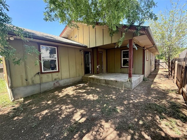 back of property with board and batten siding, a patio area, and a fenced backyard