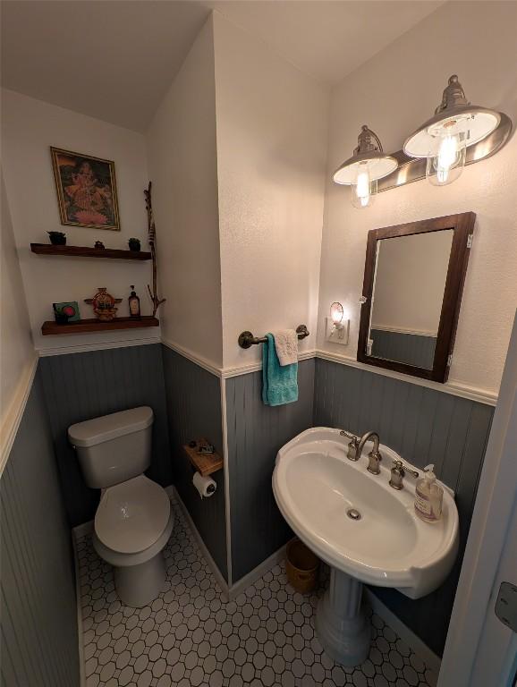 bathroom featuring a sink, a wainscoted wall, and toilet