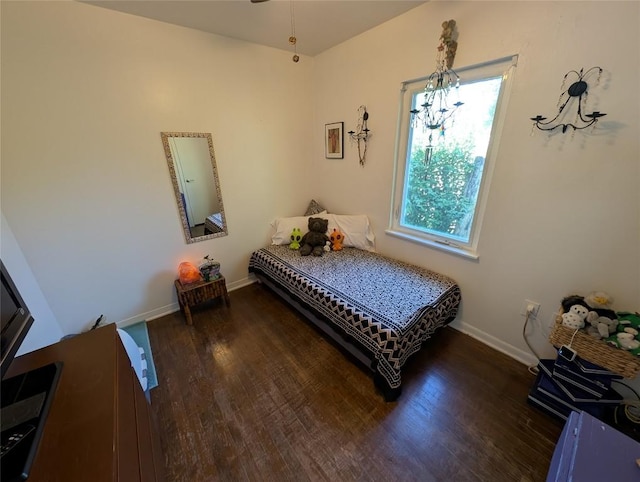 bedroom featuring a notable chandelier, multiple windows, and wood finished floors