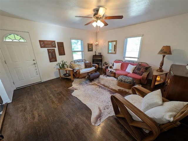 living area with baseboards, a ceiling fan, and dark wood finished floors