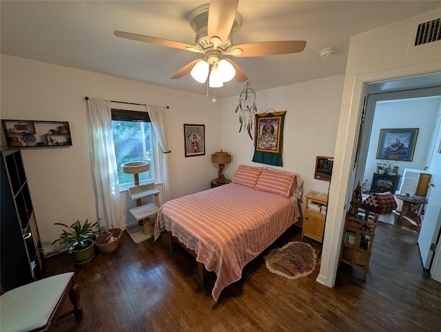 bedroom featuring a ceiling fan, visible vents, and wood finished floors