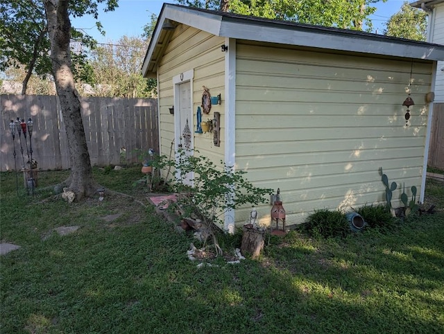 view of side of home with a lawn, fence, and an outbuilding
