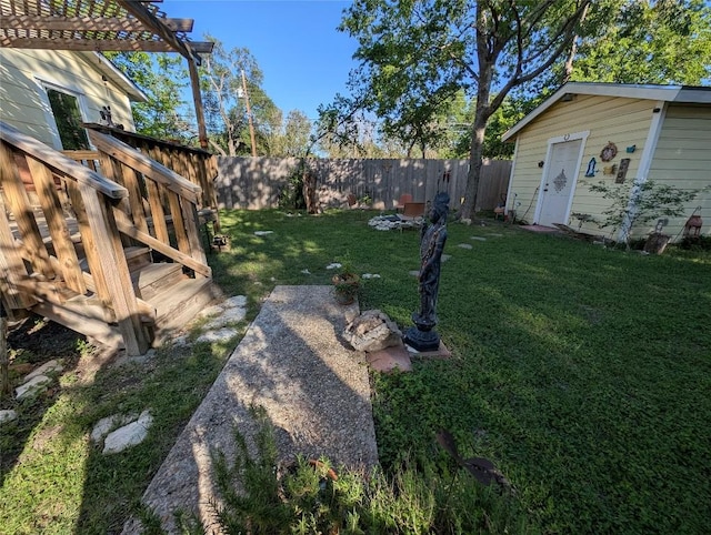 view of yard with a fenced backyard, a wooden deck, an outbuilding, and a pergola