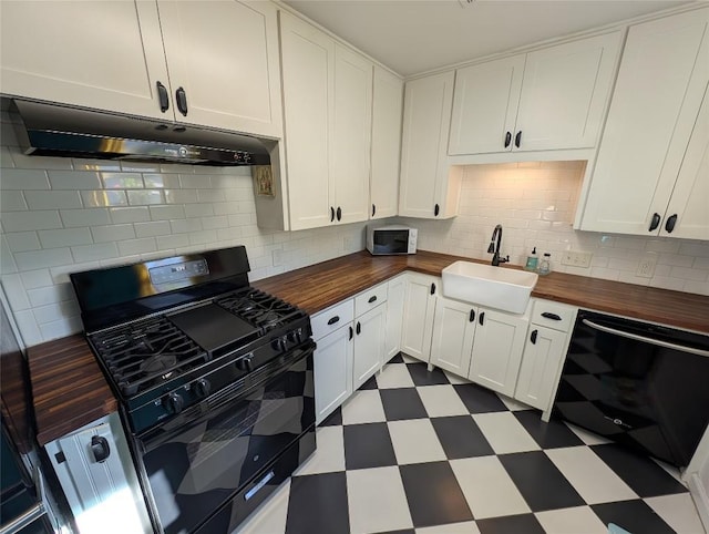 kitchen featuring a sink, wood counters, dark floors, under cabinet range hood, and black appliances