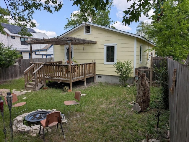 rear view of house featuring a pergola, a wooden deck, crawl space, a yard, and a fire pit
