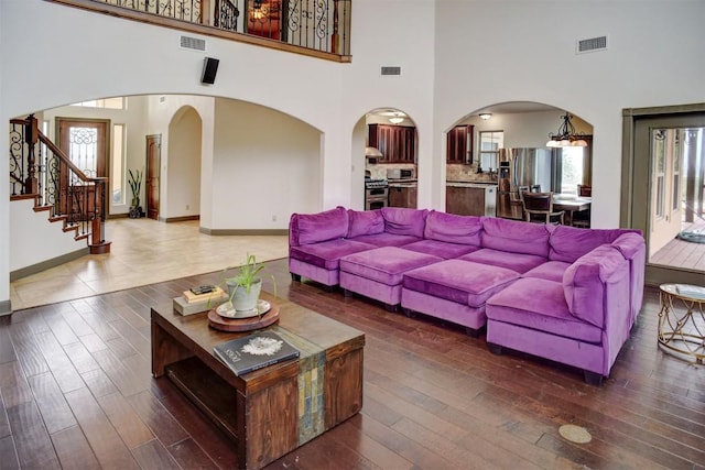 living room with arched walkways, a towering ceiling, visible vents, and plenty of natural light
