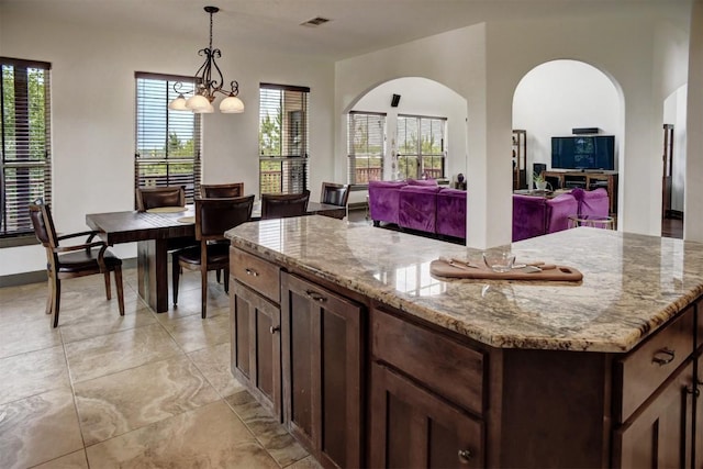 134 River Forest Dr, Bastrop, TX 78602 - kitchen featuring light stone countertops, open floor plan, decorative light fixtures, and a kitchen island