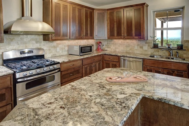 kitchen featuring light stone countertops, a sink, exhaust hood, and appliances with stainless steel finishes