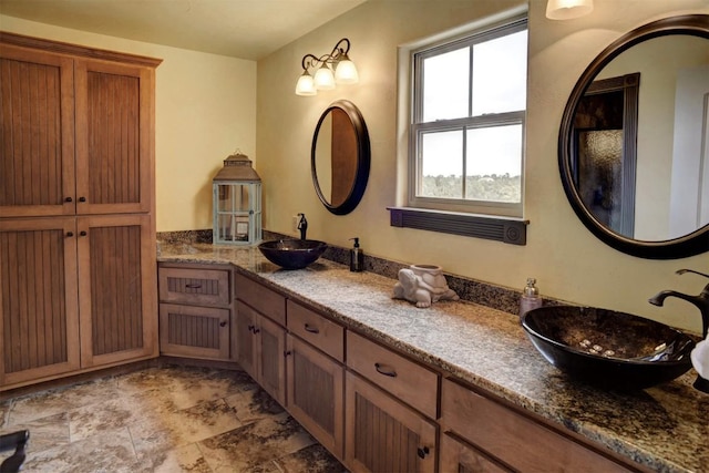 full bath featuring stone finish floor and vanity