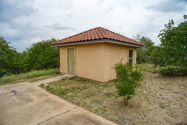 view of side of property featuring stucco siding and a tiled roof