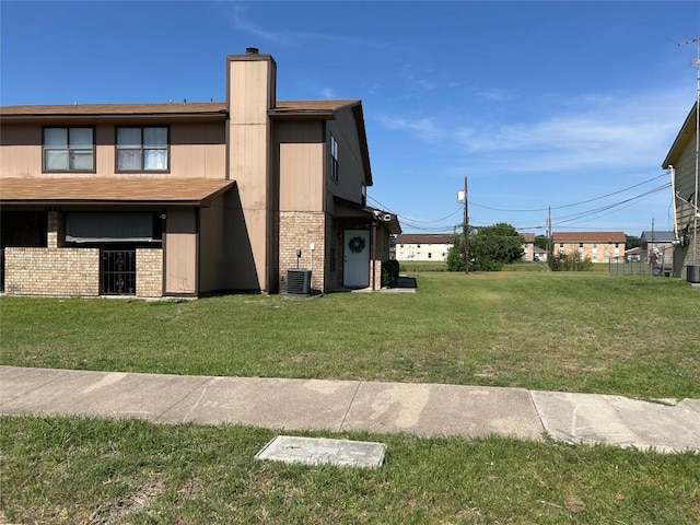 exterior space with a chimney, brick siding, and a lawn