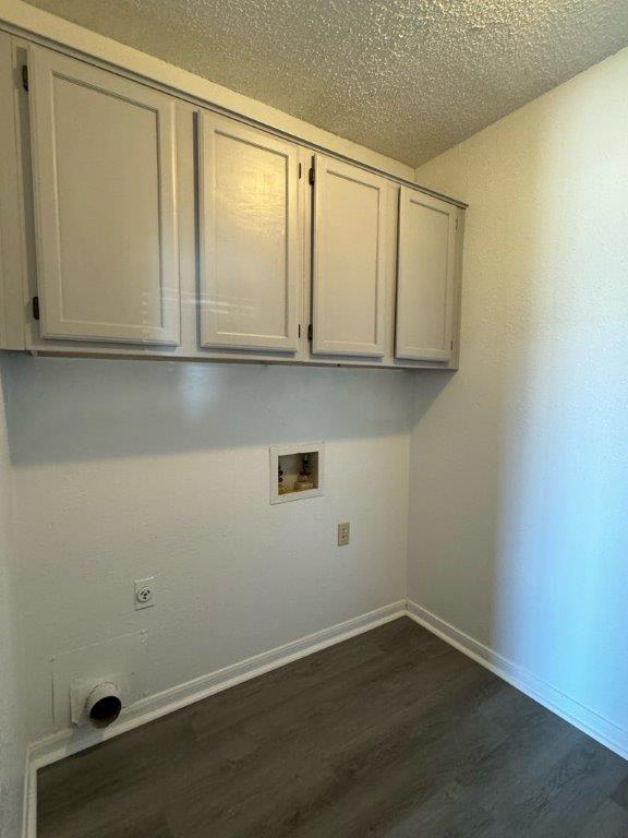 clothes washing area featuring dark wood-style floors, hookup for a washing machine, electric dryer hookup, cabinet space, and a textured ceiling