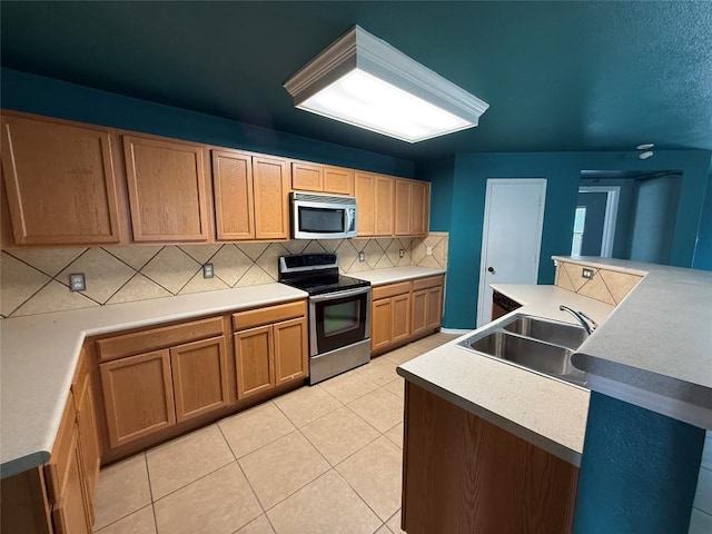 kitchen with tasteful backsplash, a sink, light tile patterned flooring, light countertops, and appliances with stainless steel finishes