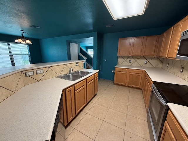 kitchen with a sink, black appliances, decorative backsplash, light countertops, and a notable chandelier