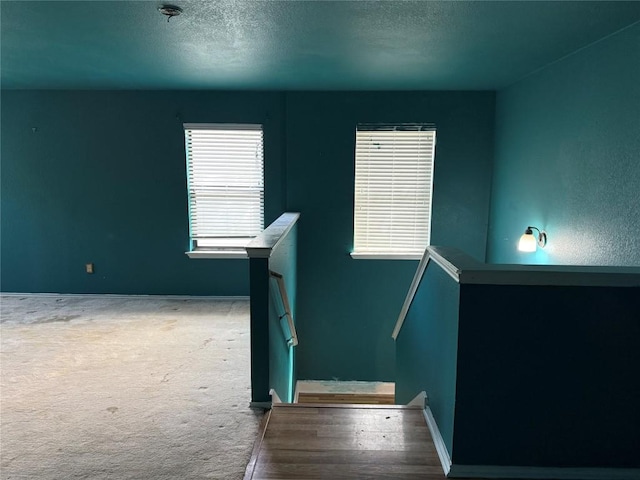 stairway with baseboards, carpet flooring, and a textured ceiling