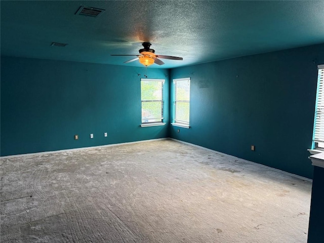 spare room with a ceiling fan, visible vents, carpet floors, and a textured ceiling