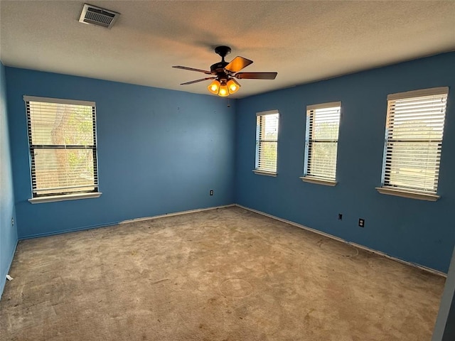 carpeted empty room with baseboards, a ceiling fan, visible vents, and a textured ceiling