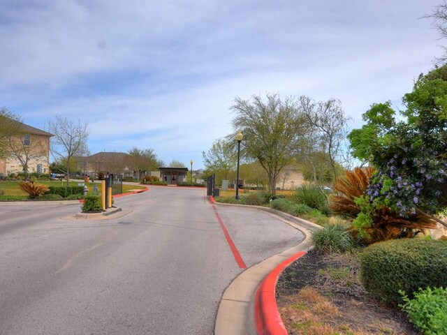 view of road with a gated entry, curbs, and street lighting