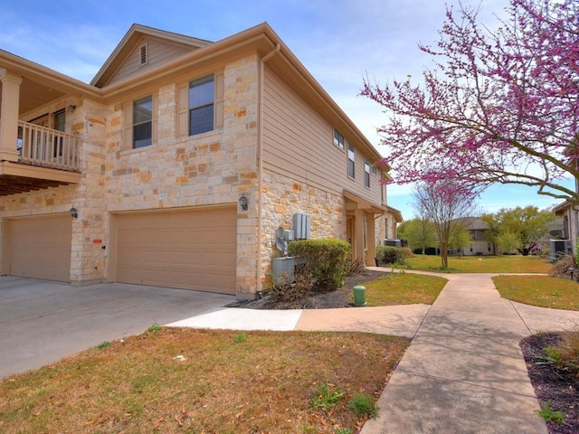 view of home's exterior with a garage, driveway, and stone siding