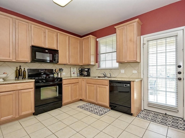 kitchen with backsplash, light brown cabinetry, a sink, and black appliances
