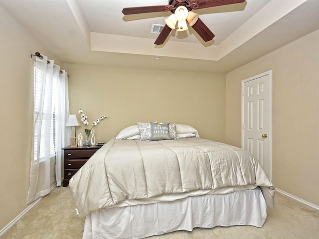 bedroom featuring visible vents, light colored carpet, and a tray ceiling
