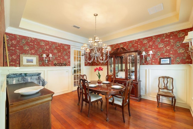 dining room with wainscoting, wood-type flooring, a chandelier, and visible vents