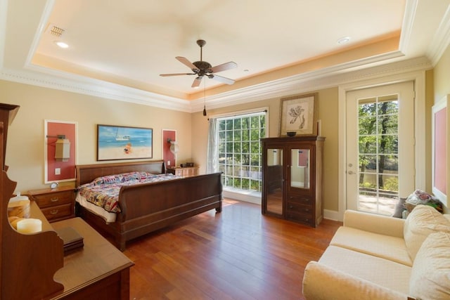 bedroom with a raised ceiling, wood finished floors, ornamental molding, and access to outside