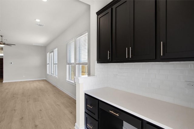 316 Ridgewell Loop, Georgetown, TX 78633 - kitchen with light wood-style floors, decorative backsplash, dark cabinets, light countertops, and baseboards