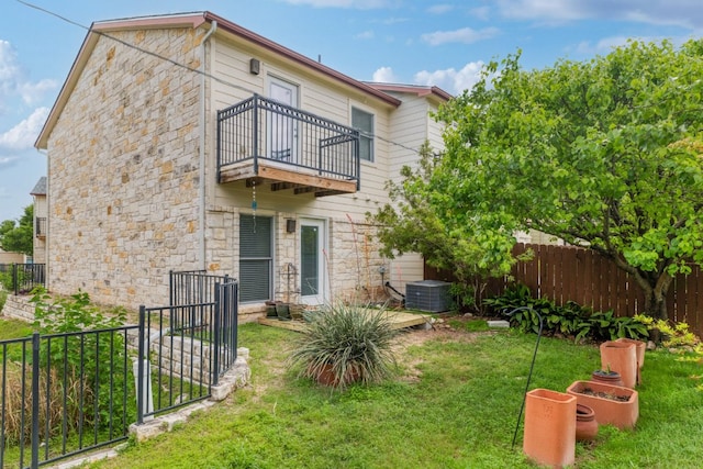 6900 E Riverside Dr Unit 24, Austin, TX 78741 - back of house featuring central AC unit, a balcony, a lawn, stone siding, and fence