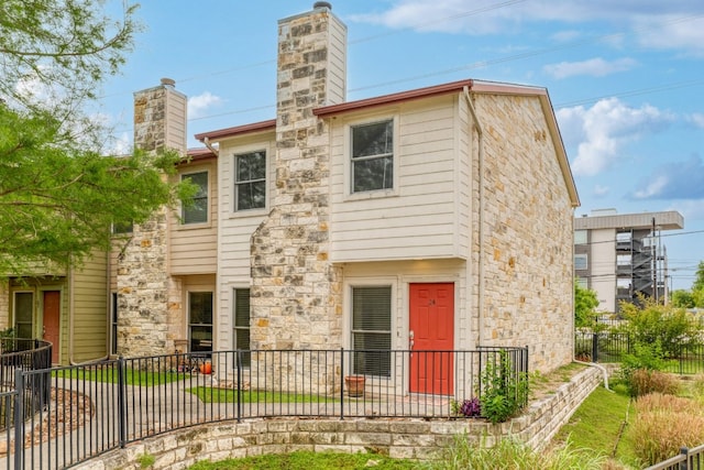 6900 E Riverside Dr Unit 24, Austin, TX 78741 - view of front of house featuring a chimney, fence, and stone siding