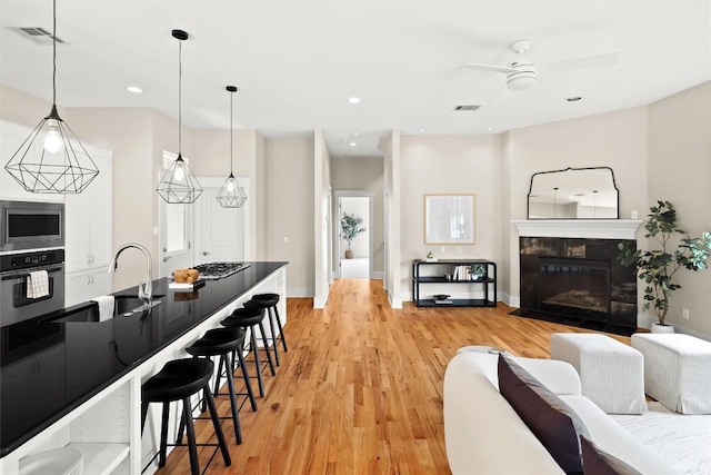 living room with a tiled fireplace, visible vents, recessed lighting, light wood-style floors, and ceiling fan