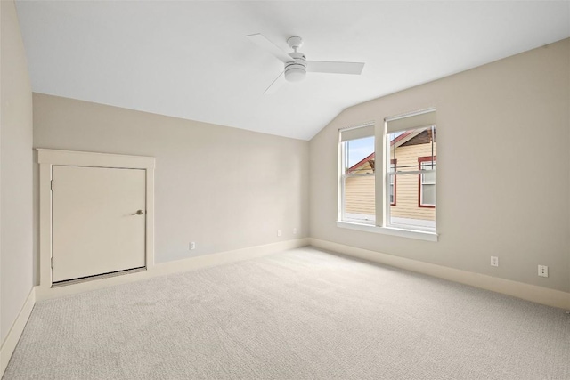 unfurnished room featuring baseboards, vaulted ceiling, carpet flooring, and ceiling fan