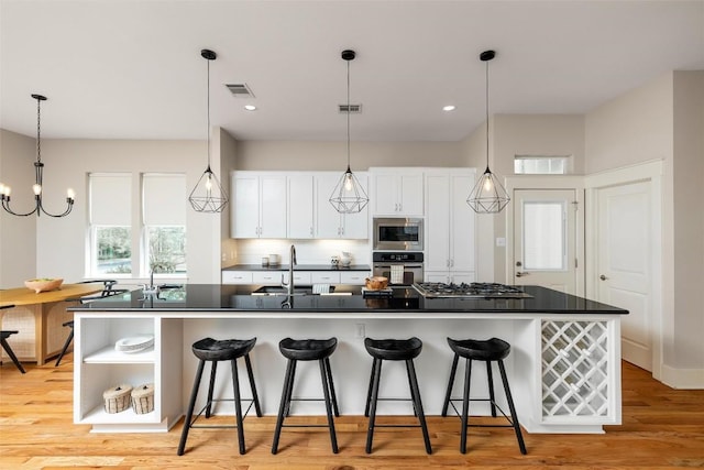 kitchen featuring white cabinets, stainless steel appliances, dark countertops, open shelves, and a breakfast bar