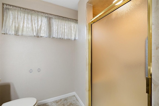 bathroom with baseboards, a shower stall, and toilet
