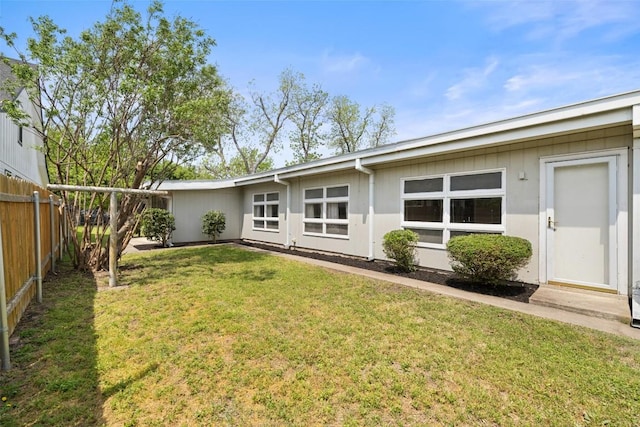 rear view of property with fence and a lawn