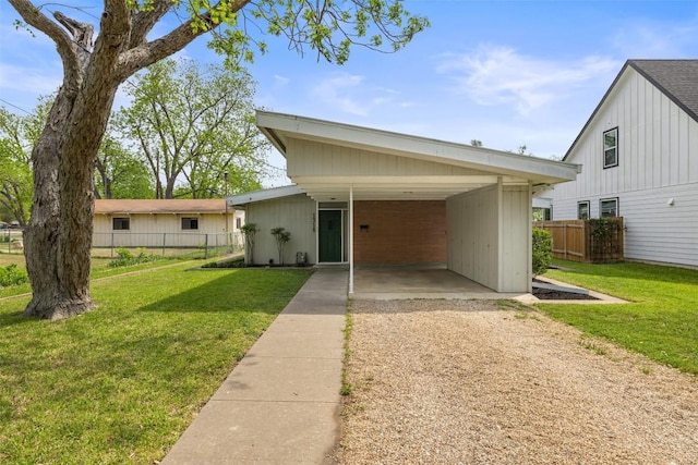 view of front of house featuring fence, dirt driveway, an attached carport, and a front yard