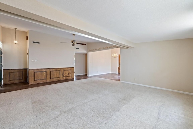 unfurnished room with wainscoting, ceiling fan with notable chandelier, visible vents, and carpet