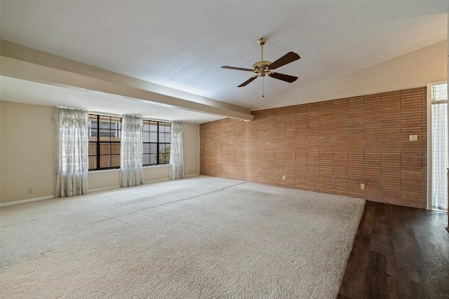 empty room featuring brick wall, baseboards, a ceiling fan, and beamed ceiling