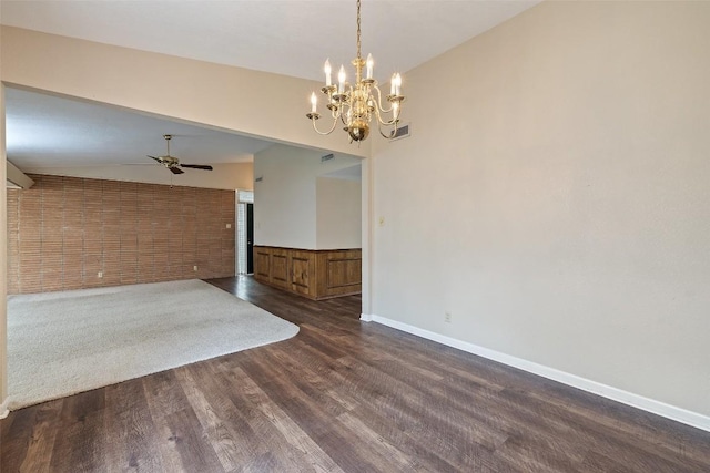 spare room with dark wood-style floors, vaulted ceiling, ceiling fan with notable chandelier, a wainscoted wall, and visible vents