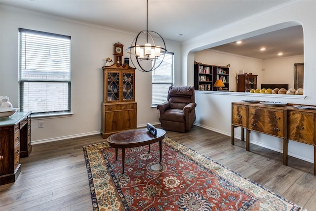 living area with arched walkways, baseboards, an inviting chandelier, wood finished floors, and crown molding