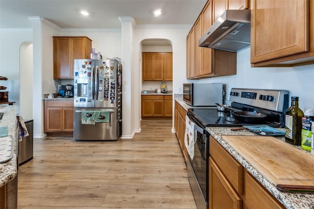 kitchen with brown cabinets, arched walkways, appliances with stainless steel finishes, ornamental molding, and ventilation hood
