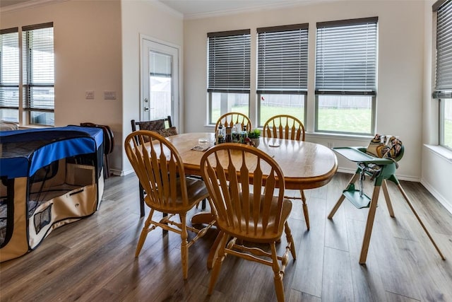 dining area with baseboards, wood finished floors, and crown molding