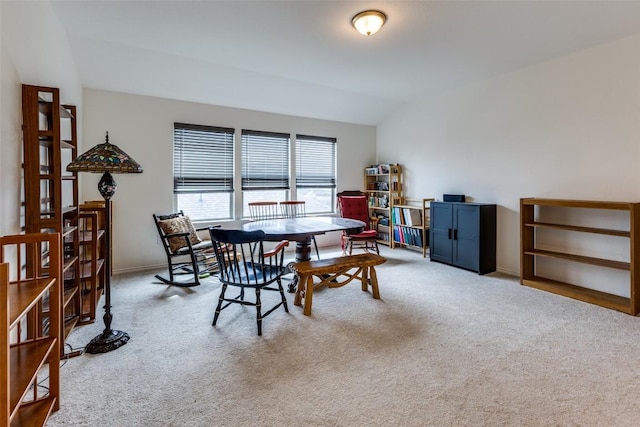 dining room featuring light carpet, lofted ceiling, and baseboards