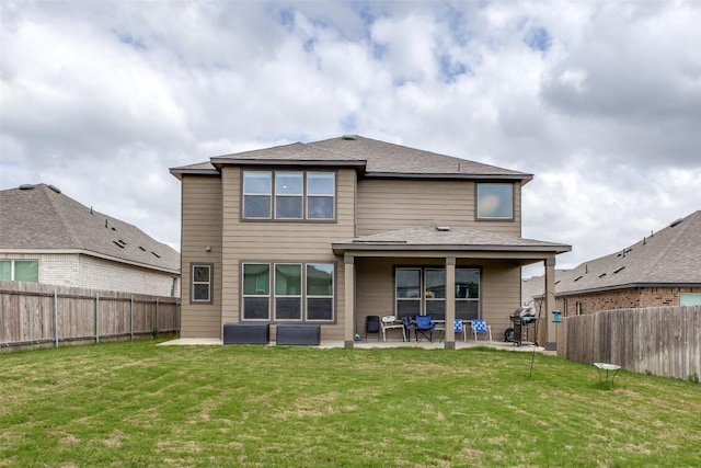 rear view of property featuring a yard, a patio area, and a fenced backyard