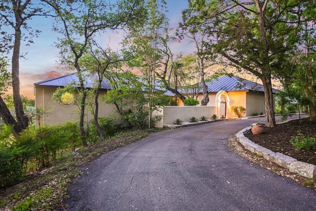 view of front of home featuring stucco siding, a standing seam roof, aphalt driveway, and metal roof