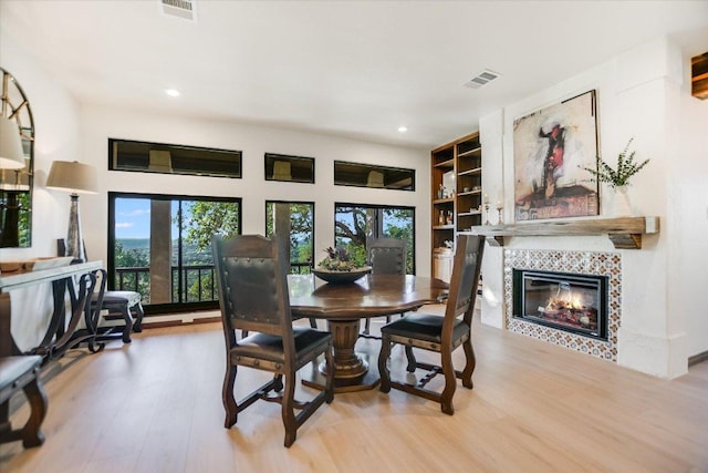 dining room with a tiled fireplace, wood finished floors, visible vents, and recessed lighting