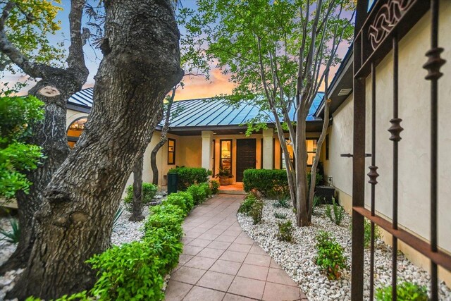 100 Mesa Dr, Wimberley, TX 78676 - property entrance with a standing seam roof, stucco siding, and metal roof